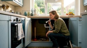 Homeowner inspecting kitchen drain pipes