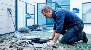 Homeowner inspecting cracked outdoor drain pipe